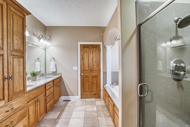 bathroom with shower with separate bathtub, double vanity, tile patterned flooring, and a textured ceiling