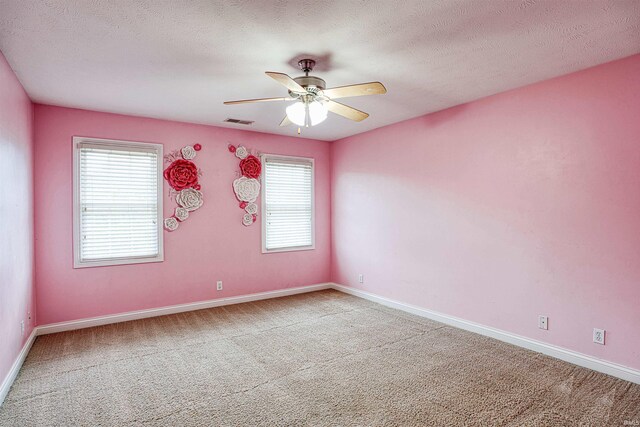 carpeted empty room with a textured ceiling, ceiling fan, and a healthy amount of sunlight