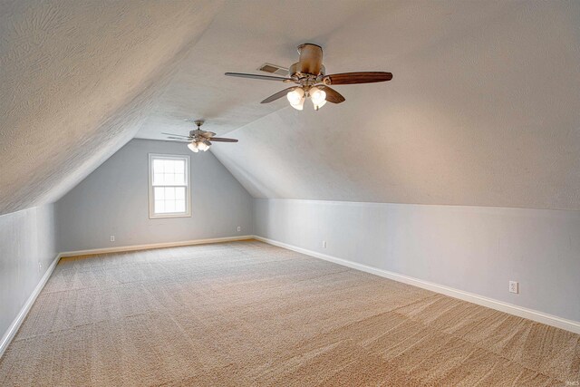 bonus room featuring ceiling fan, a textured ceiling, light carpet, and lofted ceiling