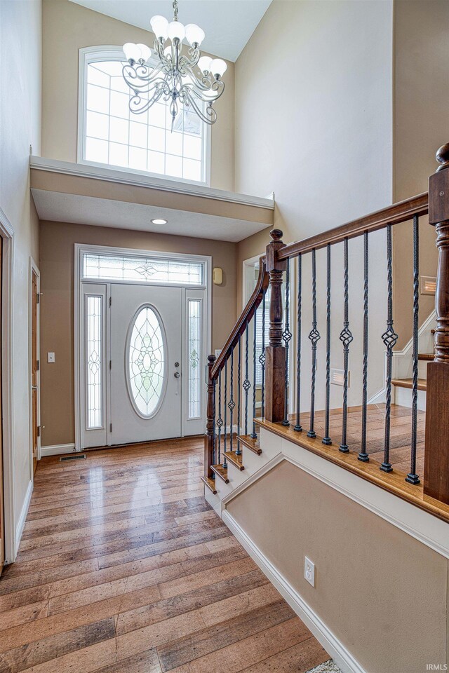 entryway with hardwood / wood-style floors, a high ceiling, and a chandelier