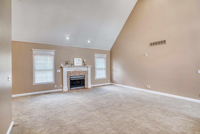 unfurnished living room with high vaulted ceiling, a tiled fireplace, and carpet flooring