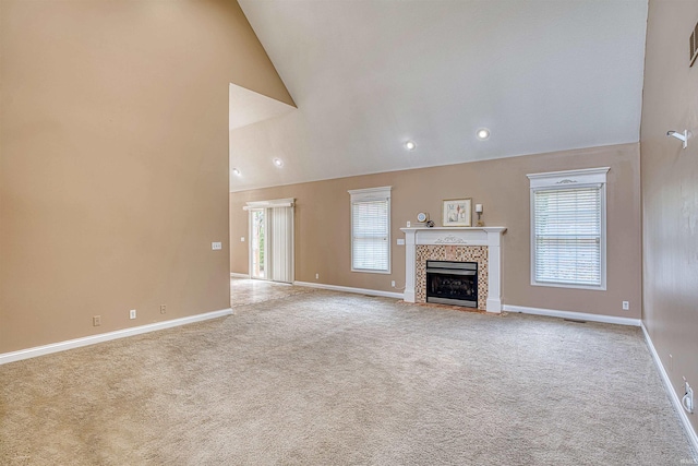 unfurnished living room featuring high vaulted ceiling, a tile fireplace, and light carpet