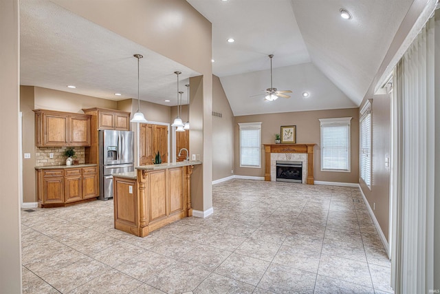 kitchen with vaulted ceiling, backsplash, stainless steel refrigerator with ice dispenser, decorative light fixtures, and kitchen peninsula