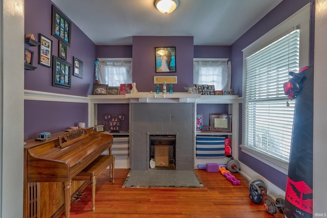 recreation room featuring hardwood / wood-style flooring, plenty of natural light, and a tile fireplace