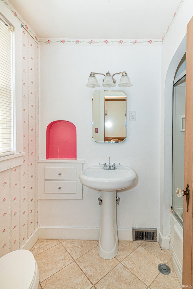 bathroom featuring toilet, a healthy amount of sunlight, shower / bathtub combination, and tile patterned floors