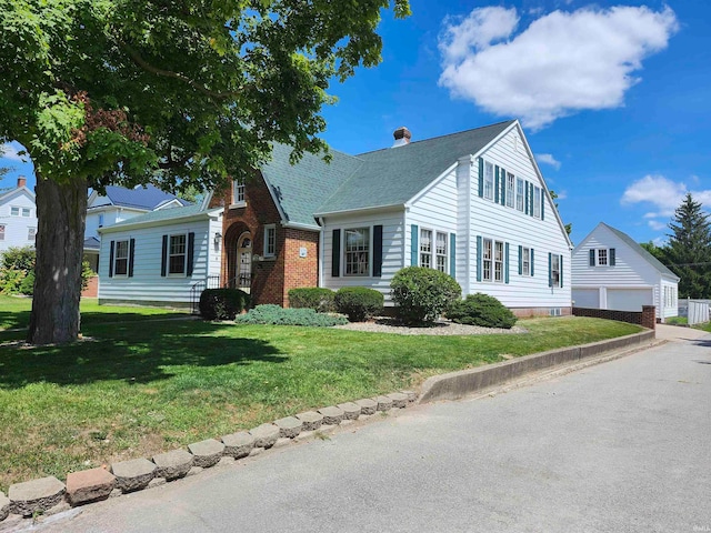 view of front facade with an outbuilding, a garage, and a front lawn