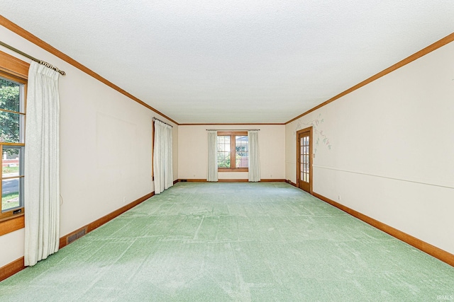 carpeted spare room featuring french doors, crown molding, and a textured ceiling