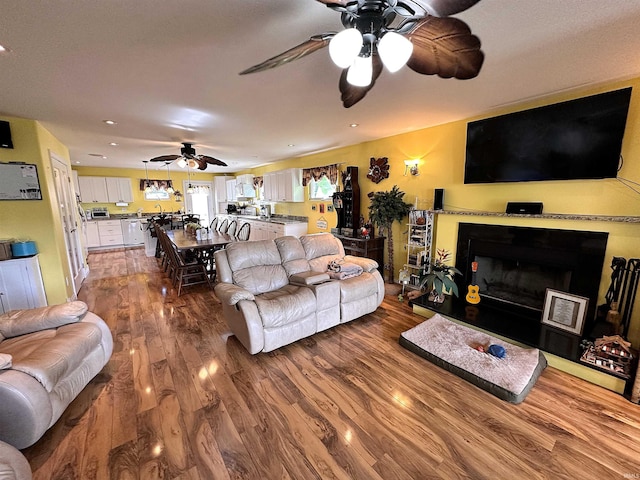 living area featuring recessed lighting, wood finished floors, ceiling fan, and a fireplace with raised hearth