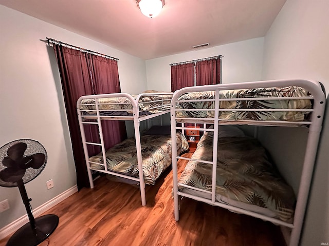 bedroom with baseboards, visible vents, and wood finished floors