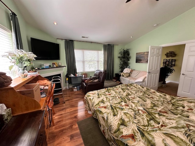 bedroom featuring a fireplace, vaulted ceiling, and dark wood-type flooring