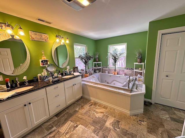 full bath with a sink, double vanity, and visible vents
