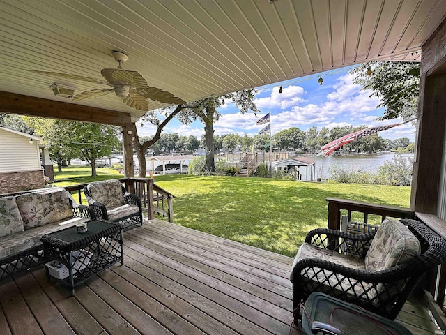 deck featuring ceiling fan, a yard, and a water view
