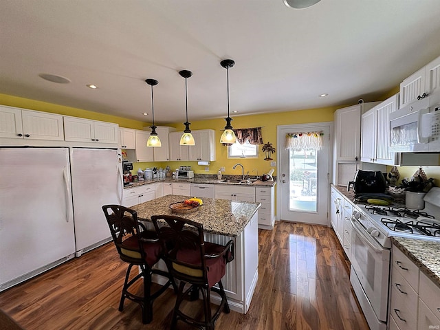 kitchen featuring white cabinetry, dark hardwood / wood-style floors, a center island, and white appliances