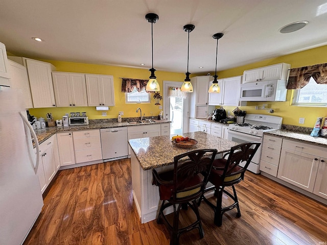 kitchen with dark wood-type flooring, white appliances, a kitchen island, white cabinetry, and hanging light fixtures