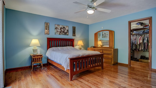 bedroom featuring a closet, a spacious closet, baseboards, and wood finished floors