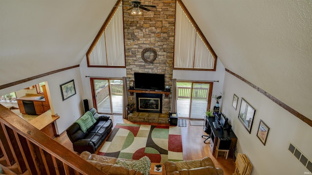 living area featuring light wood-type flooring, visible vents, a fireplace, and a towering ceiling