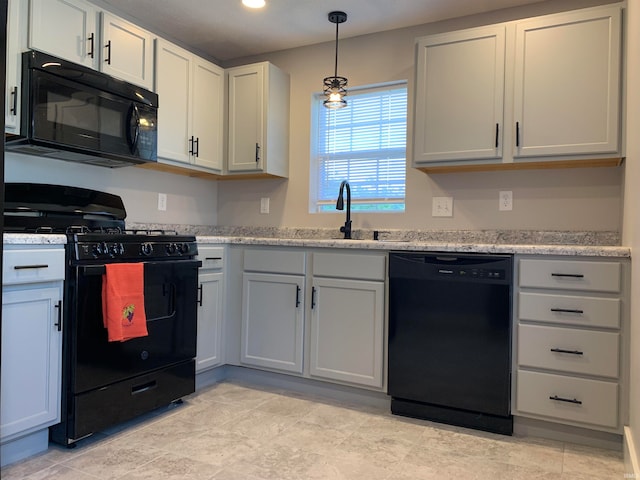 kitchen featuring light stone counters, light tile patterned floors, sink, decorative light fixtures, and black appliances