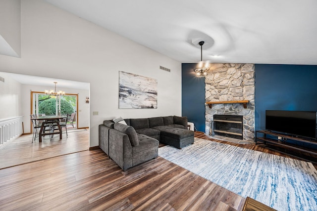 living room with a fireplace, a chandelier, wood-type flooring, and lofted ceiling