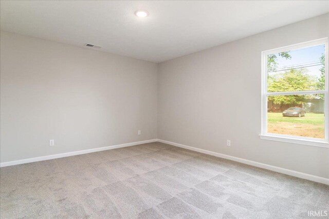 spare room with light carpet, visible vents, and baseboards