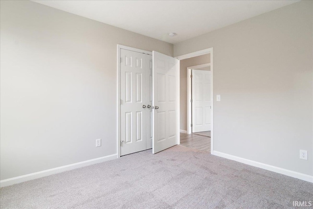 unfurnished bedroom with a closet, baseboards, and carpet flooring