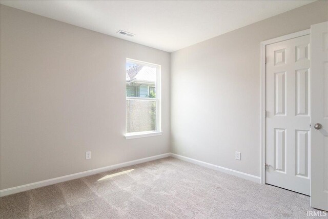 unfurnished room featuring baseboards, visible vents, and light colored carpet