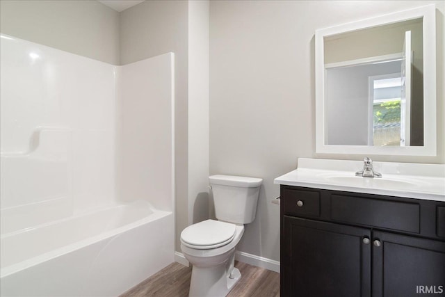 bathroom with toilet, shower / bath combination, wood finished floors, vanity, and baseboards