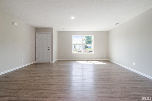 unfurnished room with visible vents, a textured ceiling, baseboards, and wood finished floors