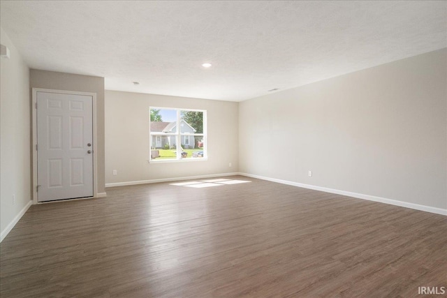 spare room featuring a textured ceiling, baseboards, and wood finished floors