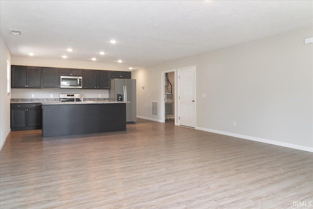 kitchen with baseboards, appliances with stainless steel finishes, open floor plan, and light wood-style floors