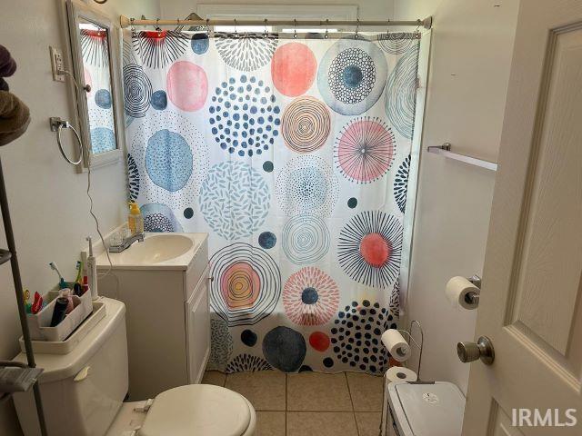 bathroom with tile patterned floors, curtained shower, vanity, and toilet