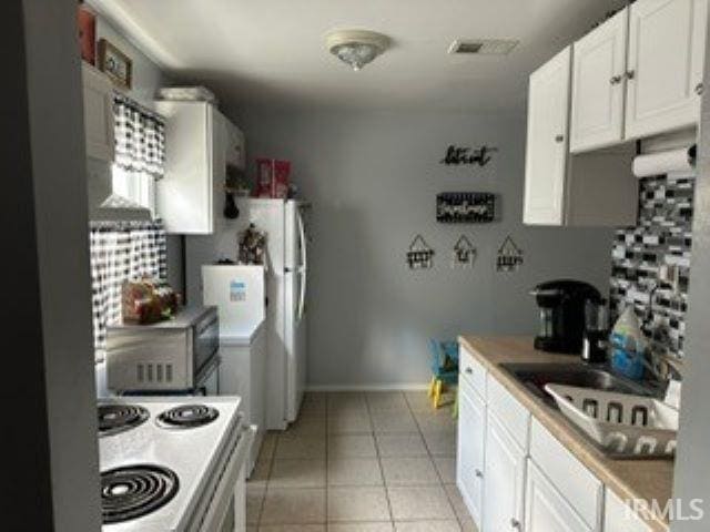 kitchen with light tile patterned floors, range, and white cabinets