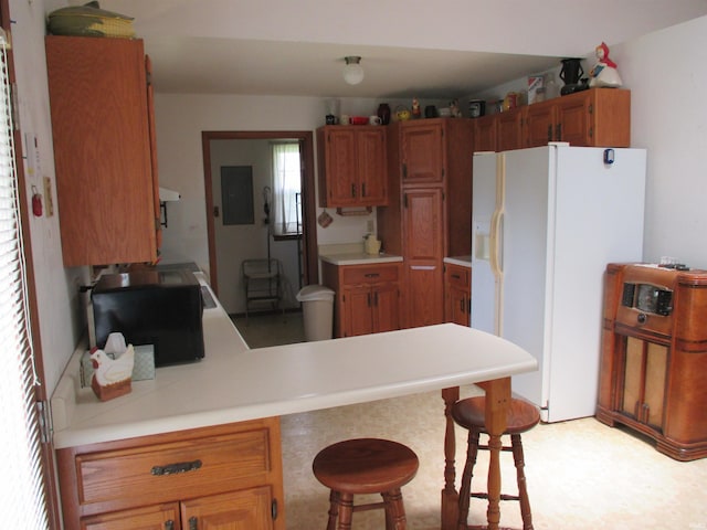 kitchen featuring a kitchen breakfast bar, electric panel, kitchen peninsula, and white refrigerator with ice dispenser