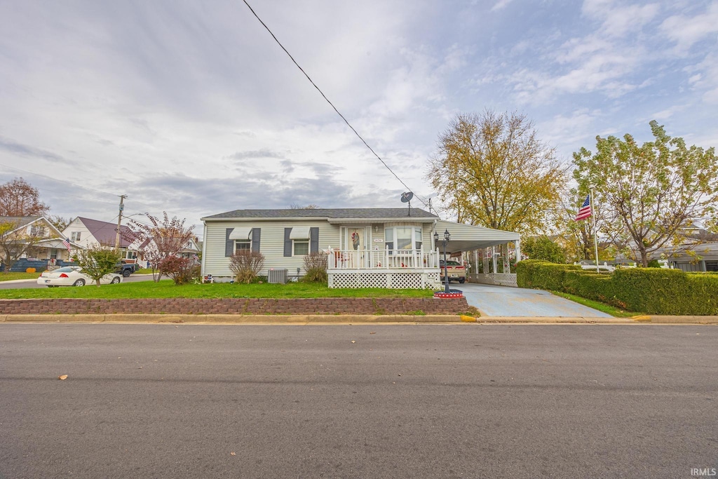 view of front of property with a front lawn, a carport, and cooling unit