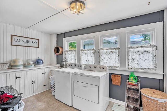 laundry room with washing machine and clothes dryer, cabinets, and light tile patterned flooring