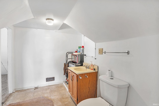 bathroom featuring tile patterned flooring, vaulted ceiling, vanity, and toilet