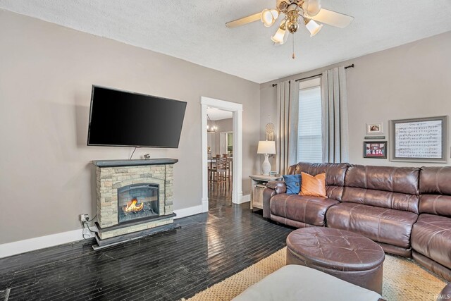 living room featuring hardwood / wood-style flooring, ceiling fan, a textured ceiling, and a stone fireplace