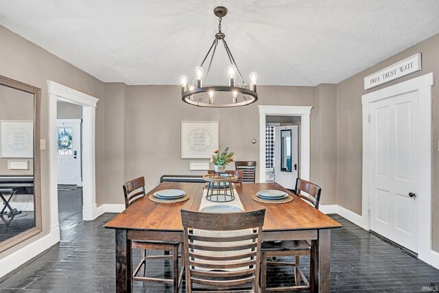 dining space featuring dark hardwood / wood-style flooring, a notable chandelier, and a textured ceiling