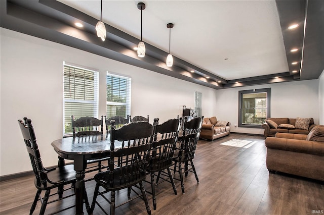 dining area with dark hardwood / wood-style flooring and a raised ceiling