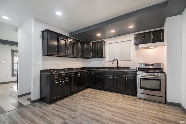 kitchen featuring sink, tasteful backsplash, stainless steel gas range oven, and light hardwood / wood-style flooring