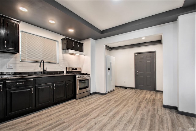 kitchen featuring sink, light hardwood / wood-style floors, stainless steel gas range oven, and white refrigerator with ice dispenser