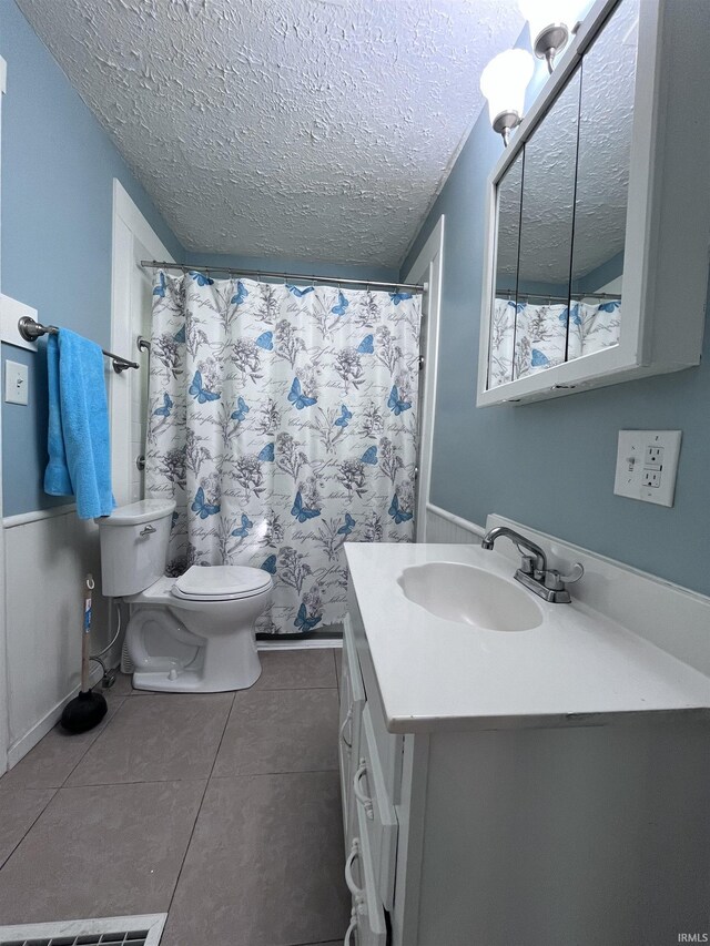 bathroom featuring a shower with curtain, toilet, tile patterned flooring, vanity, and a textured ceiling