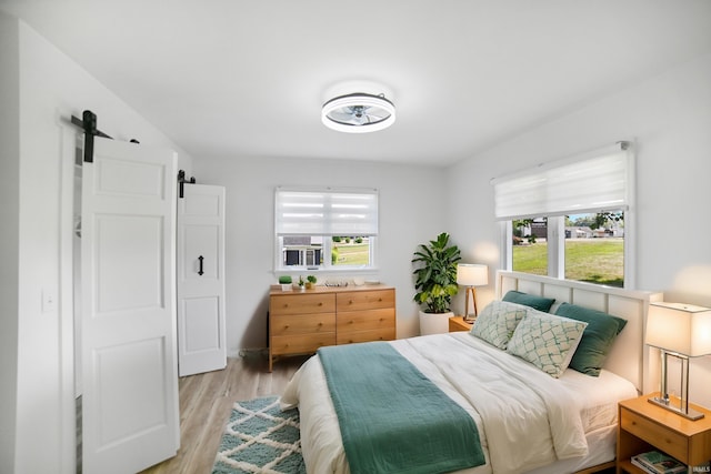 bedroom with light wood-type flooring and a barn door