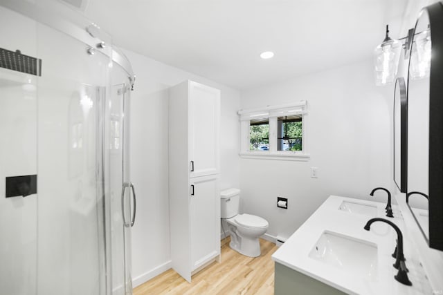 bathroom with hardwood / wood-style flooring, toilet, a shower with door, and vanity