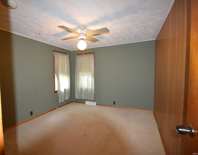 empty room featuring wood walls, ceiling fan, and carpet floors