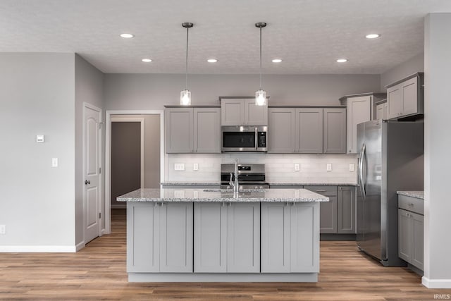 kitchen featuring appliances with stainless steel finishes, backsplash, light wood-style floors, and gray cabinetry