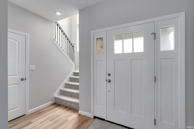 foyer entrance featuring light wood-style floors, stairs, baseboards, and recessed lighting