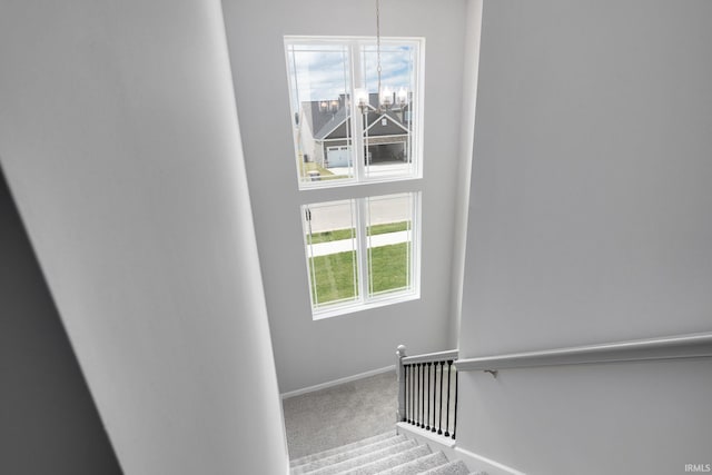 stairway with a chandelier, carpet flooring, and baseboards