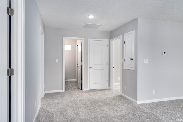 interior space with carpet flooring, visible vents, baseboards, and a textured ceiling