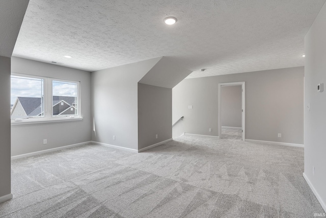 additional living space featuring carpet floors, baseboards, and a textured ceiling