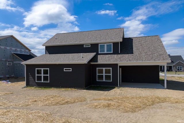 view of front of property with a patio area and roof with shingles